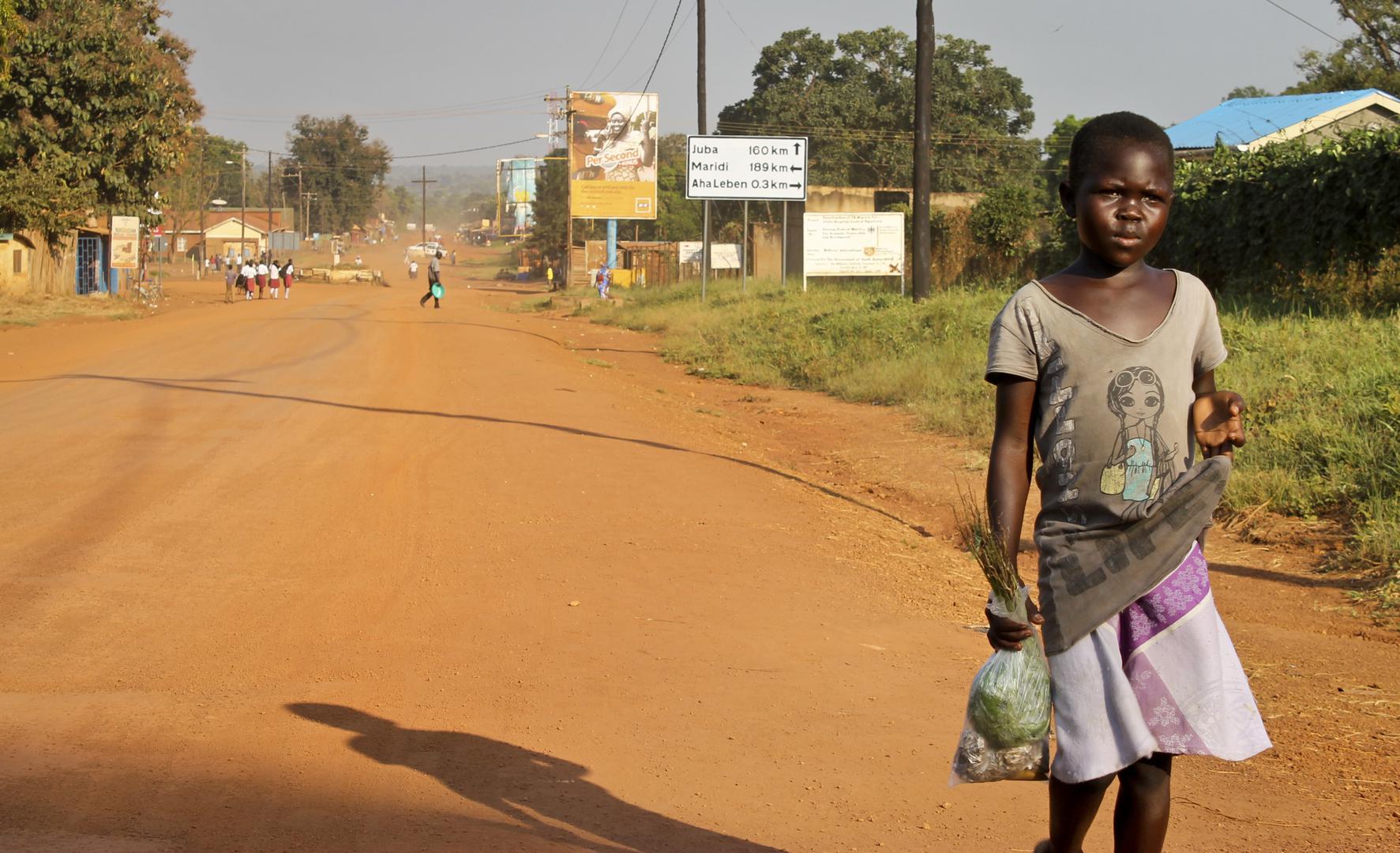 Young girl walks down a dusty street in Yei