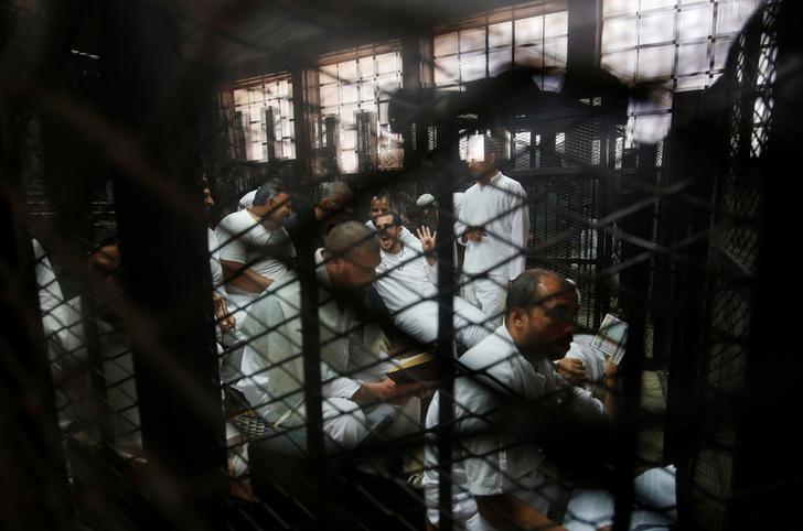 معتقلون يجلسون وراء القضبان خلال محاكمة 738 من أعضاء "الإخوان المسلمين" بتهمة الاعتصام المسلح في ميدان رابعة، في محكمة في ضواحي القاهرة، مصر، 31 مايو/أيار 2016.