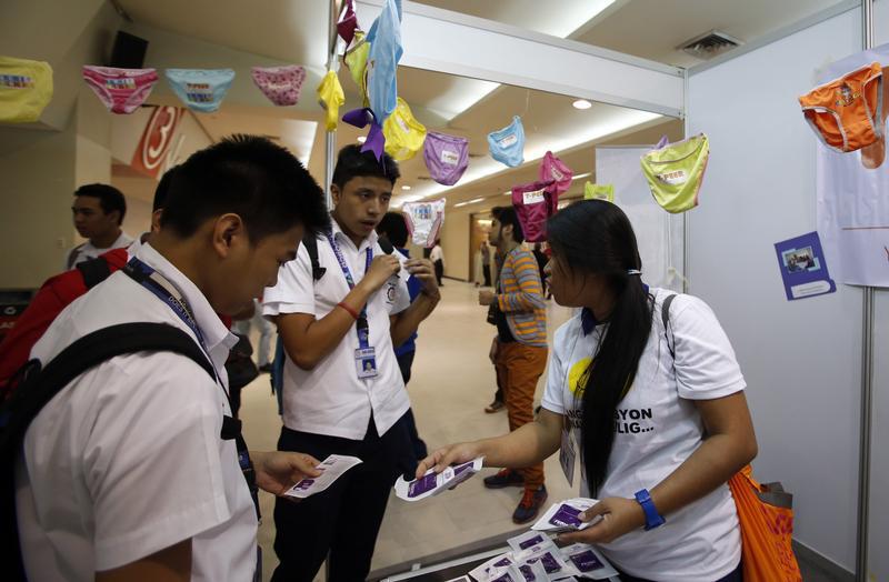 Students receive free condoms at an event organized by the United Nations Population Fund in Mandaluyong, Metro Manila, July 11, 2014.