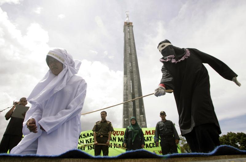 Murni Amris, an Acehnese woman, is caned as part of her sentence in the courtyard of a mosque in Aceh Besar district, Indonesia's Aceh province October 1, 2010.