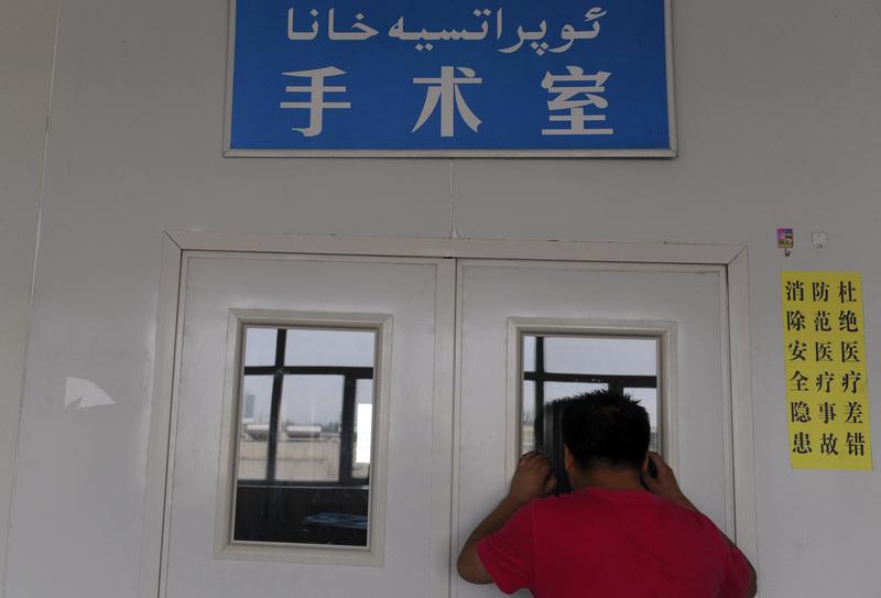 A man looks through a window on the door of an operating room as his wife undergoes a caesarean section at a hospital in Shaya county, Xinjiang Uighur Autonomous Region June 4, 2012.