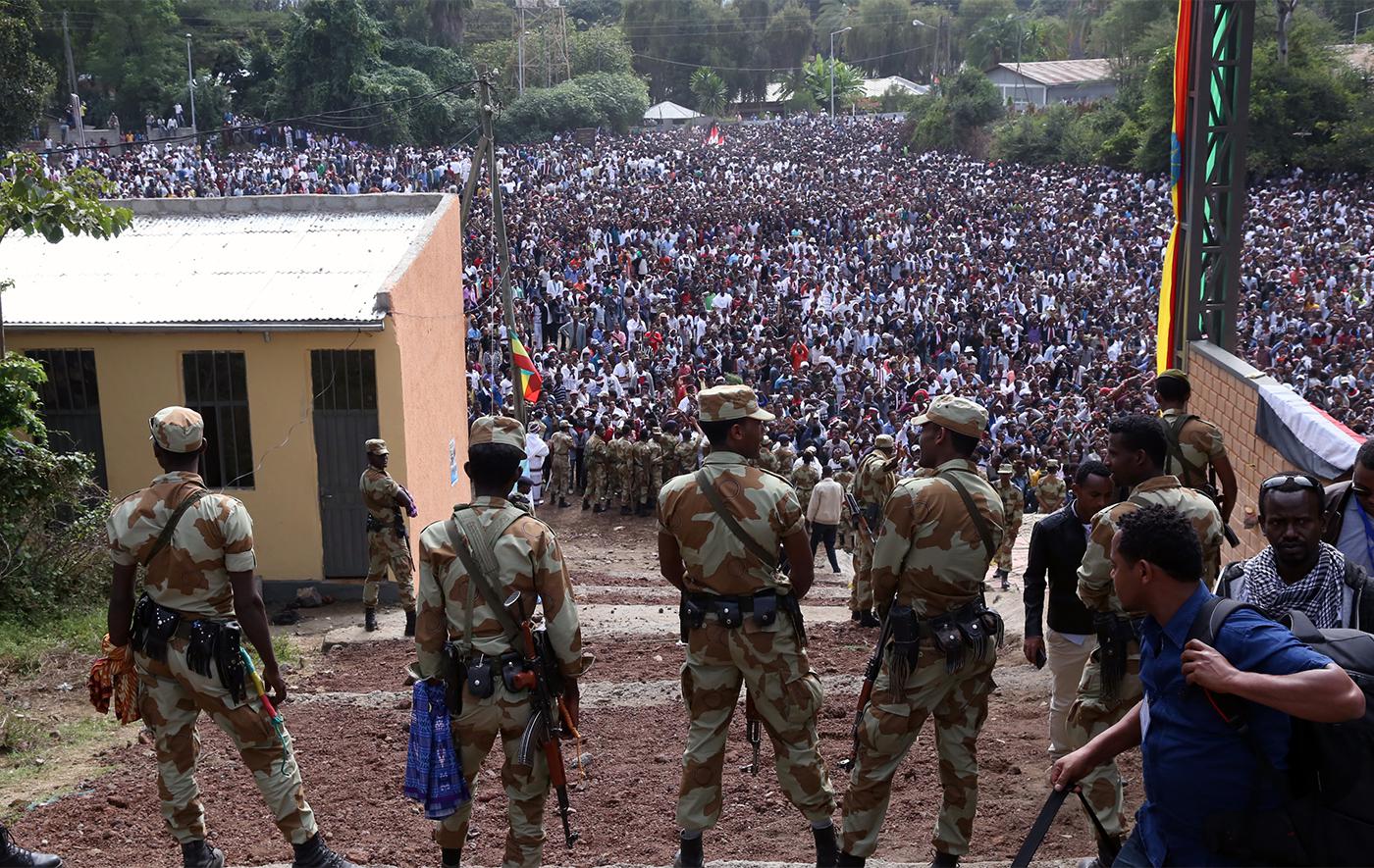Armed security officials watch as protesters stage a protest against government during the Irreechaa cultural festival in Bishoftu, Ethiopia on October 02, 2016.