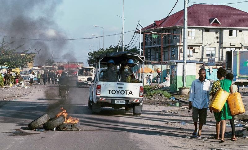 Des Casques bleus de la mission de maintien de la paix en RD Congo (MONUSCO) passent devant des pneus en flammes lors d’une patrouille pendant les manifestations contre l’échec de la mise en œuvre de l’accord de la Saint-Sylvestre, à Kinshasa, le 10 avril