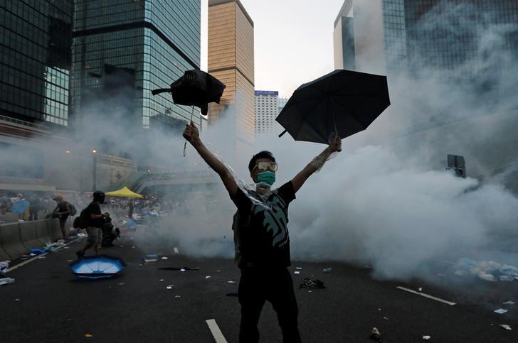 A protester raises his umbrellas after riot police fire tear gas to disperse protesters in Hong Kong, September 28, 2014