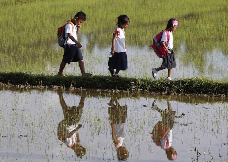 Grade school students are reflected in the water as they walk home after attending classes in Mogpog, Marinduque, the Philippines, on August 14, 2015.