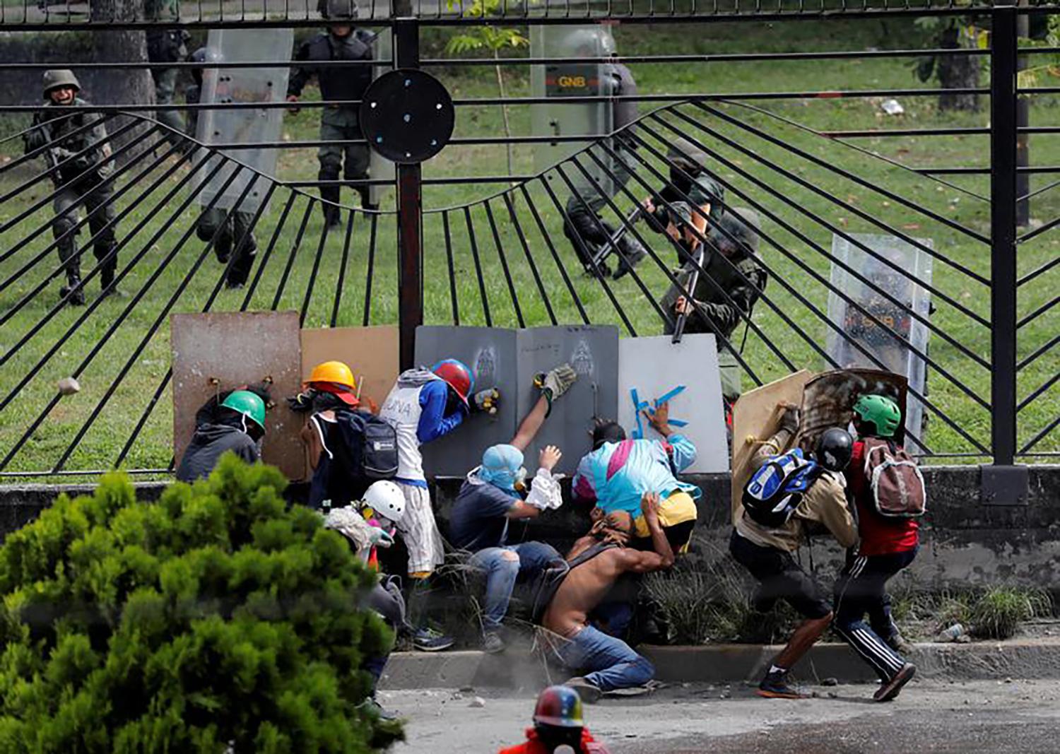 Manifestantes se enfrentan a fuerzas de seguridad antidisturbios en la reja de una base aérea durante una manifestación contra el Presidente Nicolás Maduro en Caracas, Venezuela.