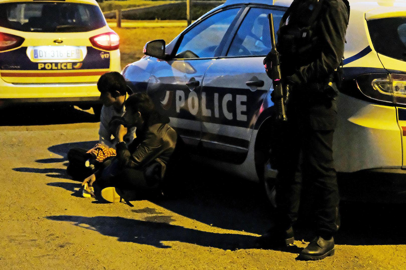 French police detain two migrants, one a 14-year-old boy, before dispersing a late-night food distribution in Calais on June 29, 2017. 