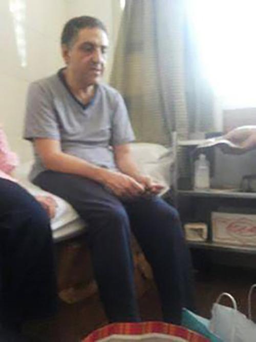 هشام جعفر يجلس على سريره في الحجز. تدهورت صحته بسرعة وهو محتجز، وصار يعاني من فقدان وزن ملحوظ وتراجع في البصر ومن مرض البروستات المزمن.