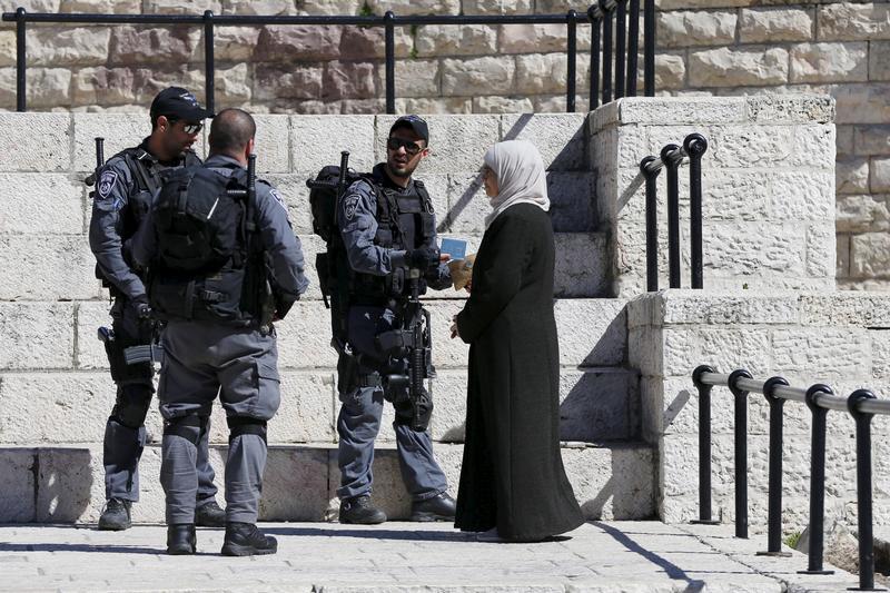 عناصر من الشرطة الإسرائيلية يدققون في هوية امرأة فلسطينية عند باب دمشق في المدينة القديمة في القدس التي تحتلها إسرائيل.  © 2016 عمار عوض/رويترز 