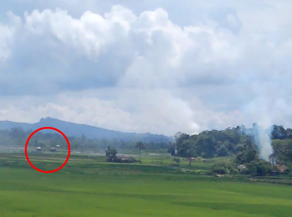 视频截图显示，两辆深色缅甸军用卡车出现在一受灾村落旁数百公尺处。