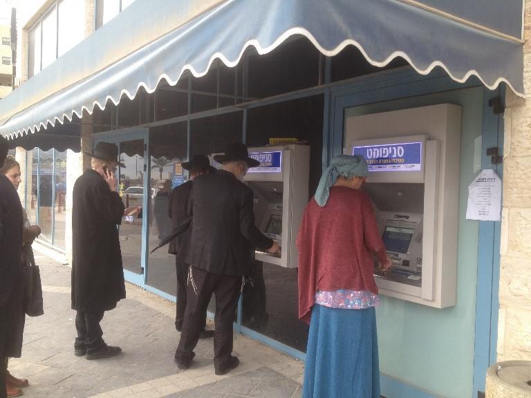 Customers use ATMs outside a bank branch in the Israeli settlement of Modi'in Ilit.