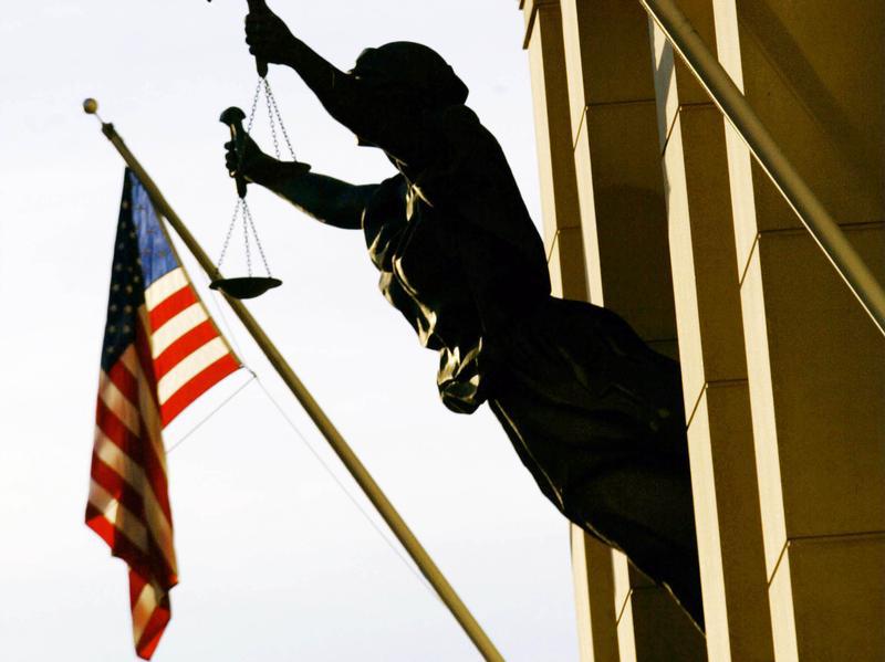العلم الأمريكي بجانب تمثال ميزان العدالة في مبنى محكمة أمريكية، 6 فبراير/شباط 2002. © 2002 رويترز 