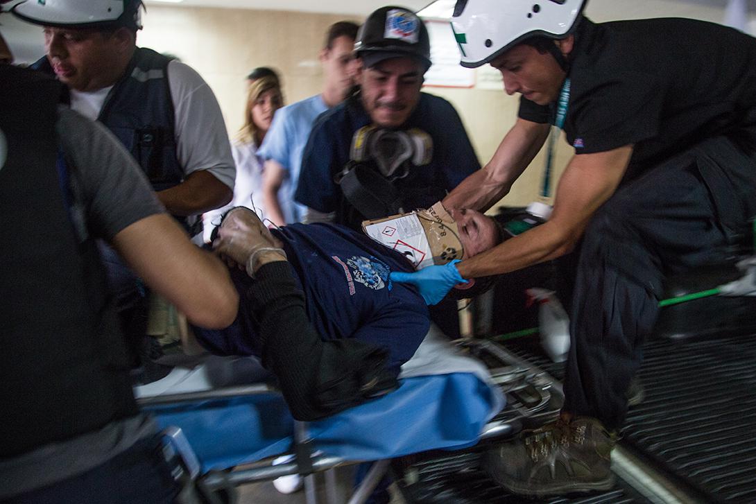 First aid volunteers from the Central University of Venezuela, part of a group known as the Green Cross, transport a person severely injured during clashes with anti-riot police to a nearby health center in Altamira, Caracas.