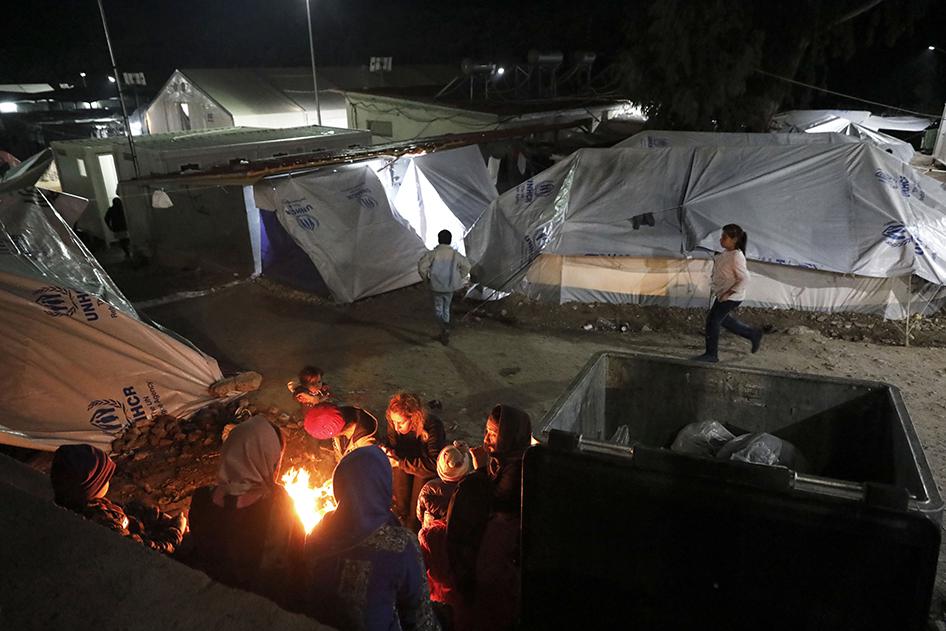 Migrants and asylum seekers gathering around a fire, inside the Moria hotspot on Lesbos island, Greece.