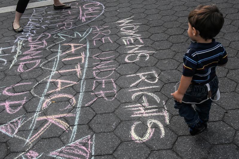 A boy looks at a writing on the ground during a protest in support of women's rights, in New York City, U.S. on October 7, 2017. 