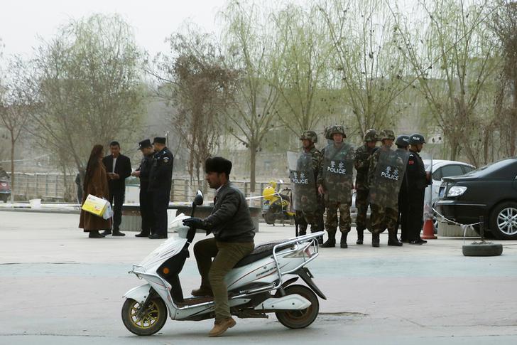 201712asia_china_xinjiang2 Police officers check the identity cards of a people as security forces keep watch in a street in Kashgar, Xinjiang Uyghur Autonomous Region, China on March 24, 2017.