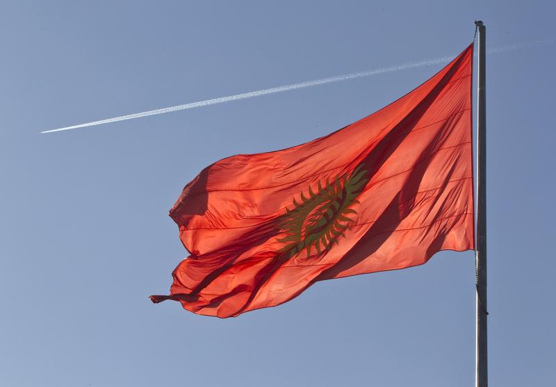 След от самолета на фоне государственного флага Кыргызстана на центральной площади Бишкека 11 марта 2013 г. 