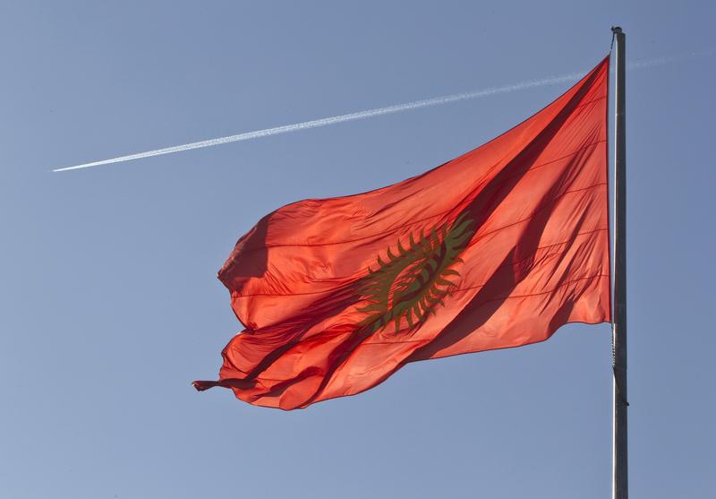 An airplane trace is seen behind a Kyrgyzstan national flag fluttering in a central square in Bishkek March 11, 2013.