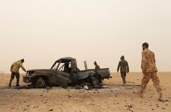 عناصر من "الجيش الوطني الليبي" يتفقدون عربة عسكرية متضررة بعد اشتباكات مع "كتائب دفاع بنغازي" في راس لانوف، ليبيا، 16 مارس/آذار 2017. 