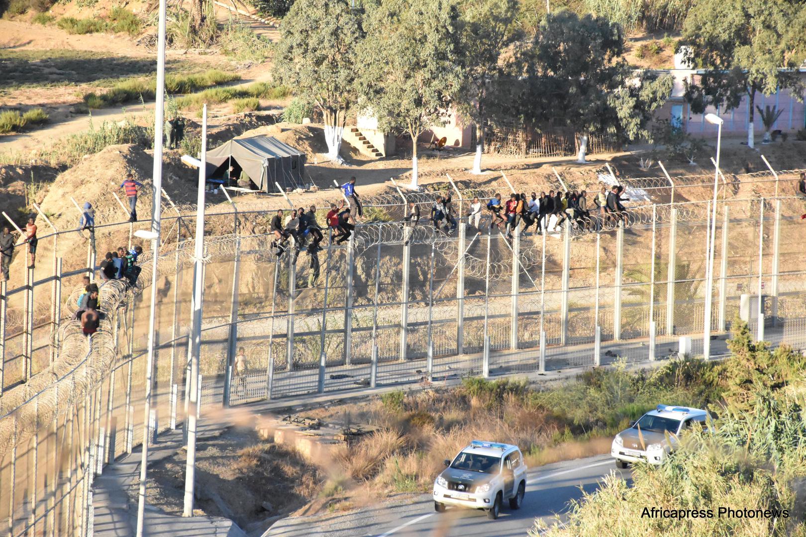 Migrantes en la cima de la cerca doble  que rodea a Ceuta, el enclave español en  África del Norte.