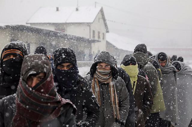 Migrants wait in line to receive free food during a snowfall outside a derelict customs warehouse in Belgrade, Serbia January 9, 2017.