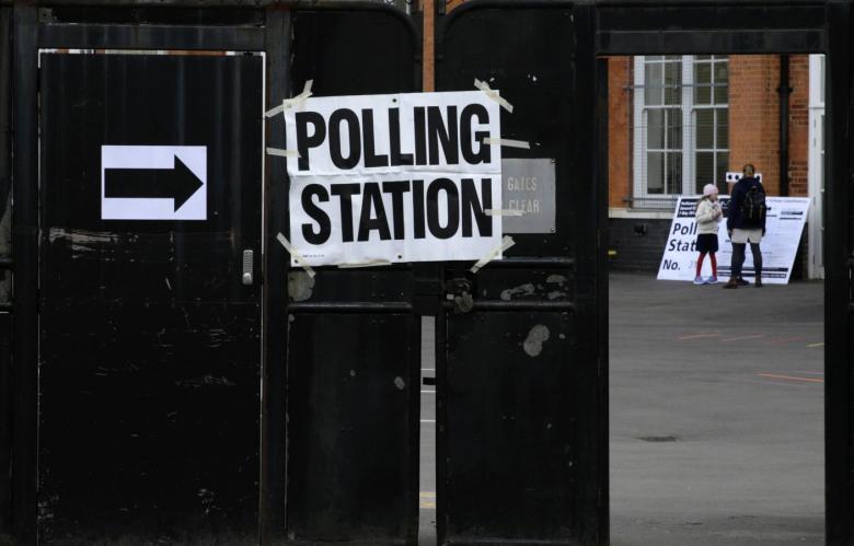 A woman stands inside a closed school that is being used as a polling station in west London, Britain May 7, 2015