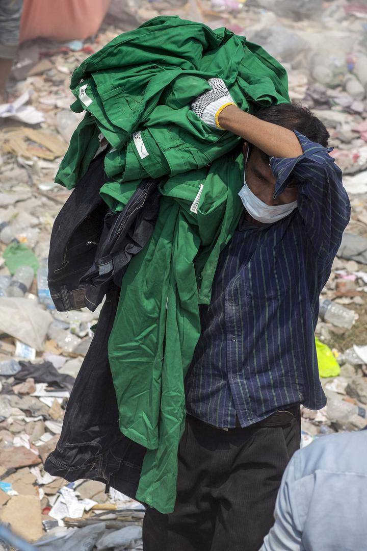 A man removes clothing bearing a brand label from the devastated area of the collapsed Rana Plaza building in Dhaka, Bangladesh, on Friday, April 26, 2013.