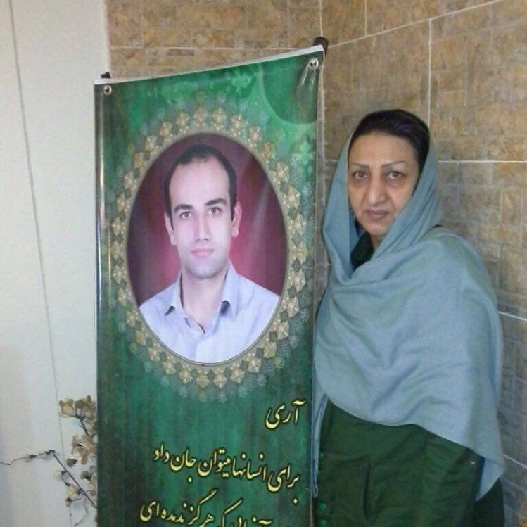 Shahnaz Karimbeigi standing next to her son's photo. 