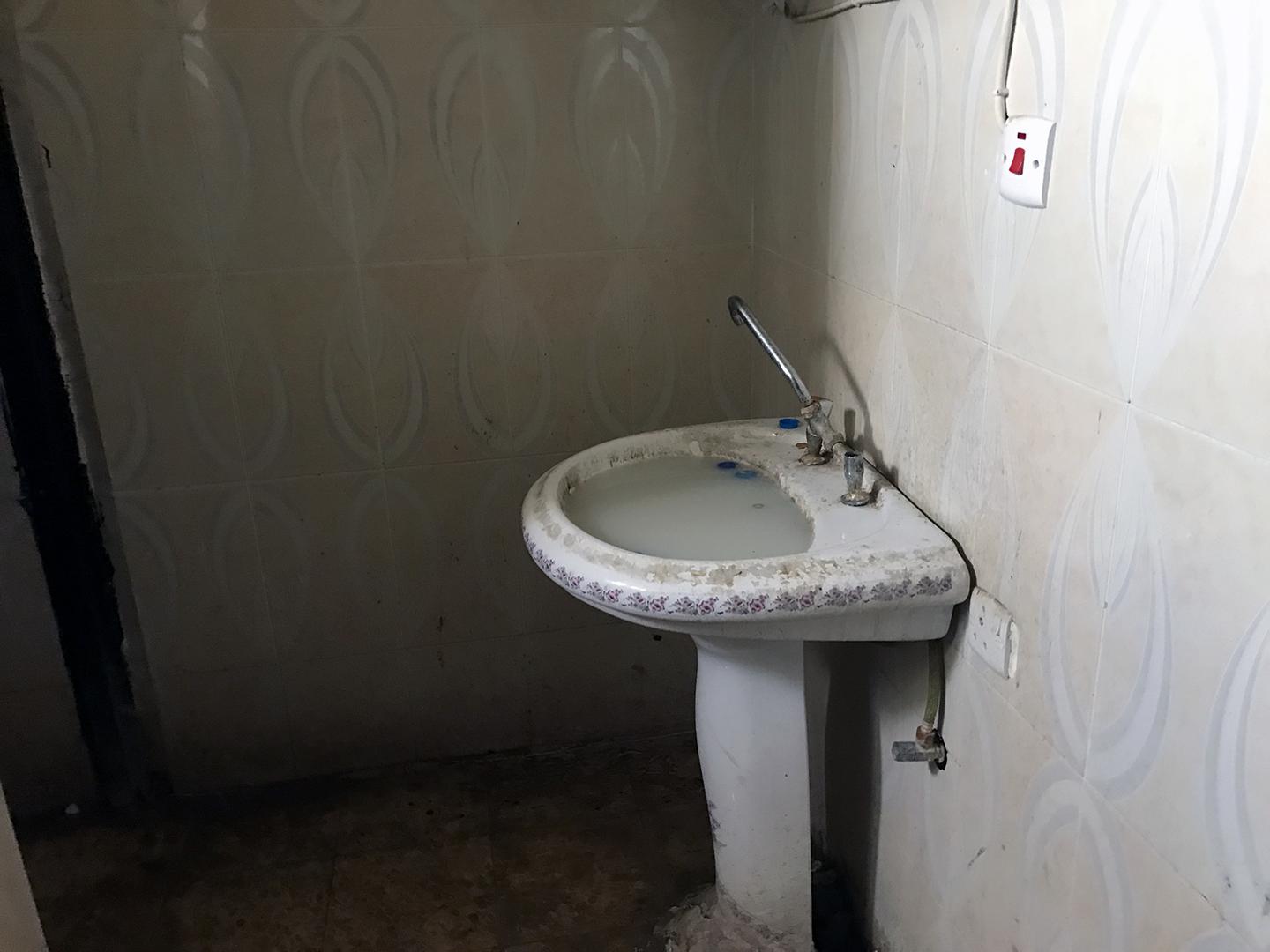 Dirty water blocks both sinks in the bathroom of Hammam al-Alil prison.