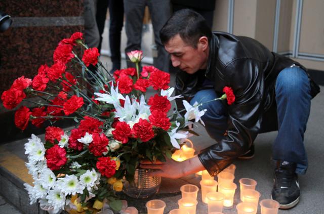 A man leaves flowers during a memorial service for victims of a blast in St.Petersburg metro, outside Sennaya Ploshchad metro station in St. Petersburg, Russia. 