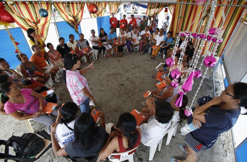 Women survivors of super typhoon Haiyan listen during a lecture on prevention of gender-based violence by a United Nations Population Fund (UNFPA) volunteer in Tacloban city in the central Philippines on December 14, 2013. 