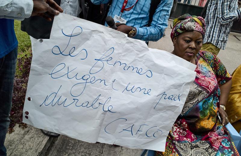 A Congolese woman holds a placard written 'Women require stable peace' as they sit in protest during talks between the opposition and the government of President Joseph Kabila outside the Conference episcopale nationale du Congo (CENCO) headquarters in th