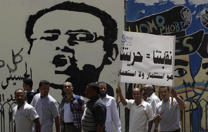 عمّال يرفعون لافتة ويهتفون بشعارات مناوئة للحكومة أثناء مظاهرة قرب ميدان التحرير في القاهرة، مصر، 29 أبريل/نيسان 2013.