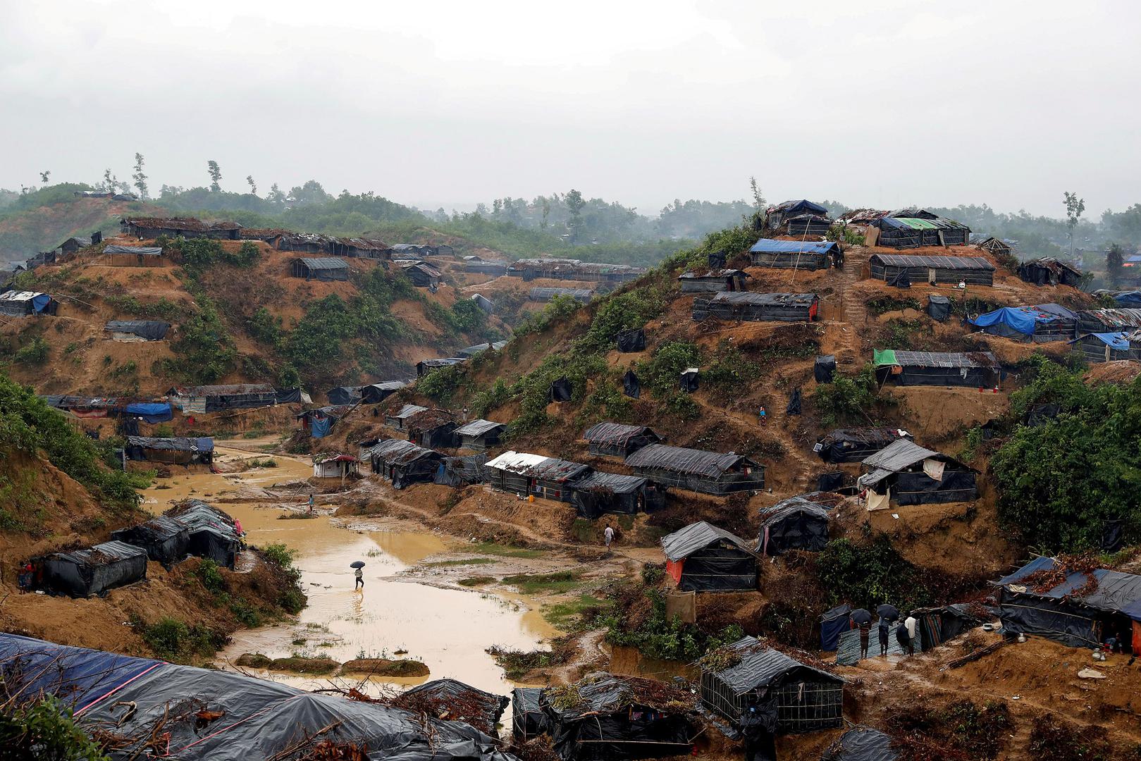 孟加拉考克斯巴扎尔县（Cox's Bazar）罗兴亚难民营，2017年9月19日。路透社摄影记者凯瑟尔・麦克诺顿（Cathal McNaughton）说：“把这个状况的完整规模呈现出来，非常重要。必须呈现出整个地形，罗兴亚人被迫栖身的土地。我守候多时，终于等到照片中所有元素到齐。画面左下方那人撑伞走在雨中，似想暂时逃避令人窒息的处境。