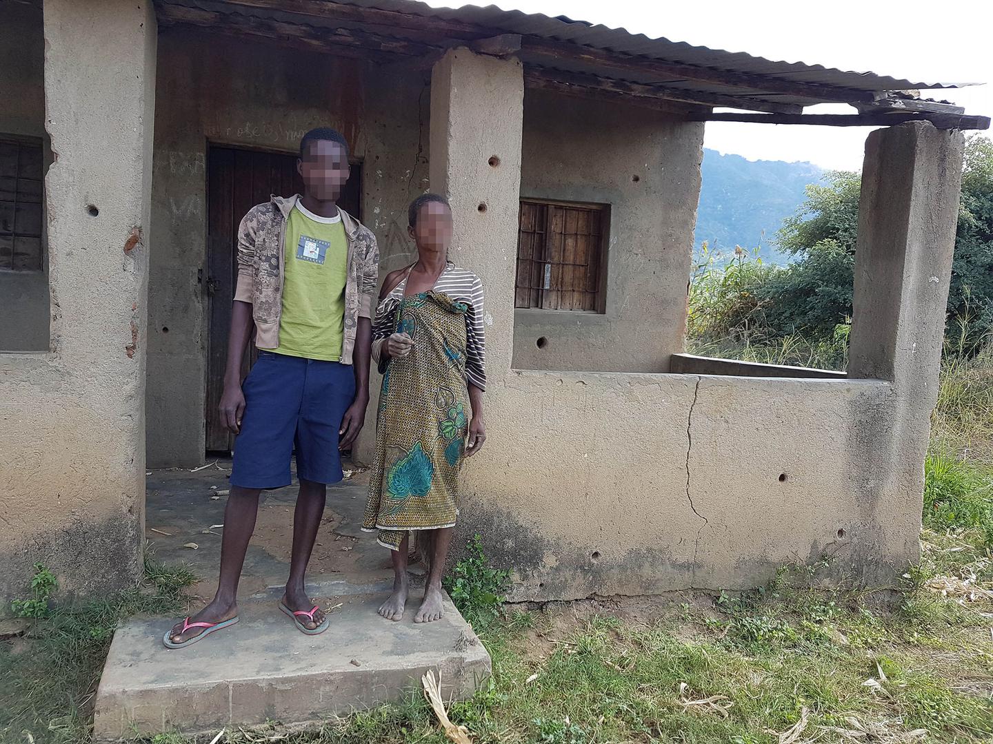A woman and her son in front of their house with bullet holes in Mukodza village, Gorongosa. They said soldiers arrived in army vehicles and fired without warning at the house in June 2016, forcing them to flee through a window. 