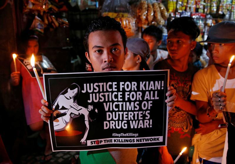 Protesters and residents hold lighted candles and placards at the wake of Kian Loyd delos Santos, a 17-year-old high school student, who was among the people shot dead last week in an escalation of President Rodrigo Duterte's war on drugs in Caloocan city