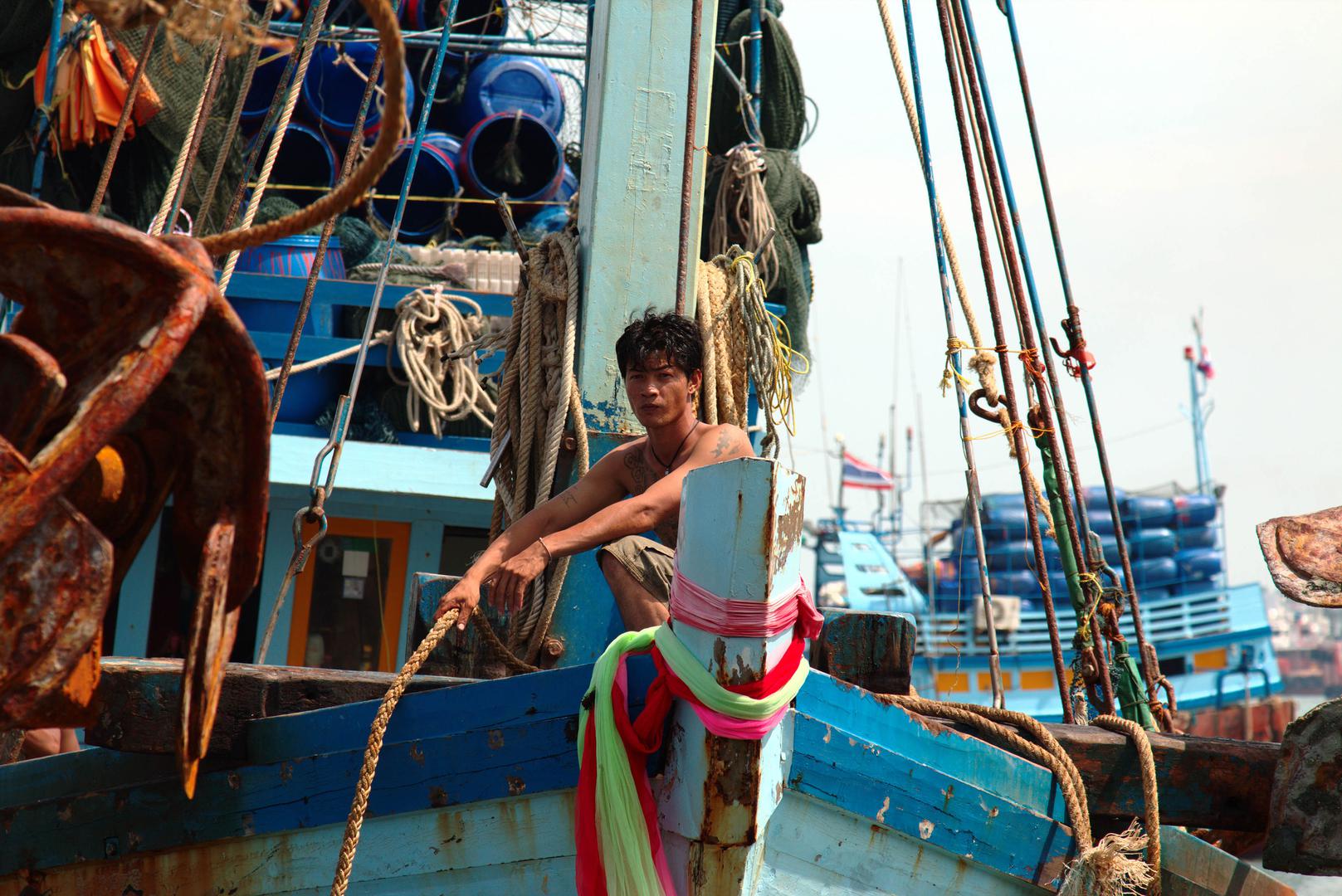 Un pêcheur thaïlandais accroupi sur la proue d'un bateau, à l’entrée du port de Pattani, dans le sud de la Thaïlande, le 12 août 2016. 