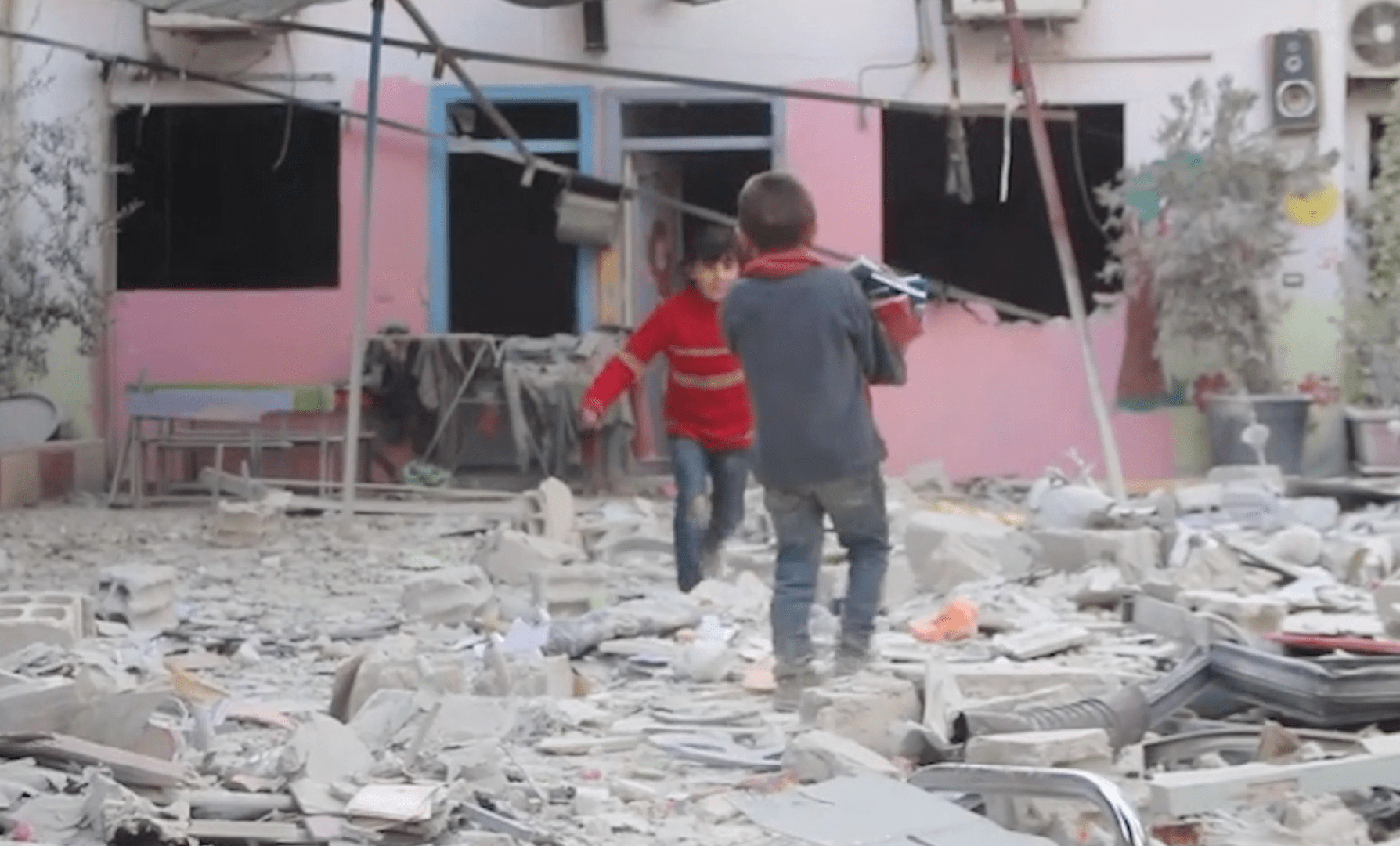 Des enfants traversent les décombres du jardin d'enfants Tamayuz («Excellence») à Hamouriyeh, en Ghouta orientale (Syrie), suite à une frappe aérienne menée par les forces syriennes et russes le 8 novembre 2017.