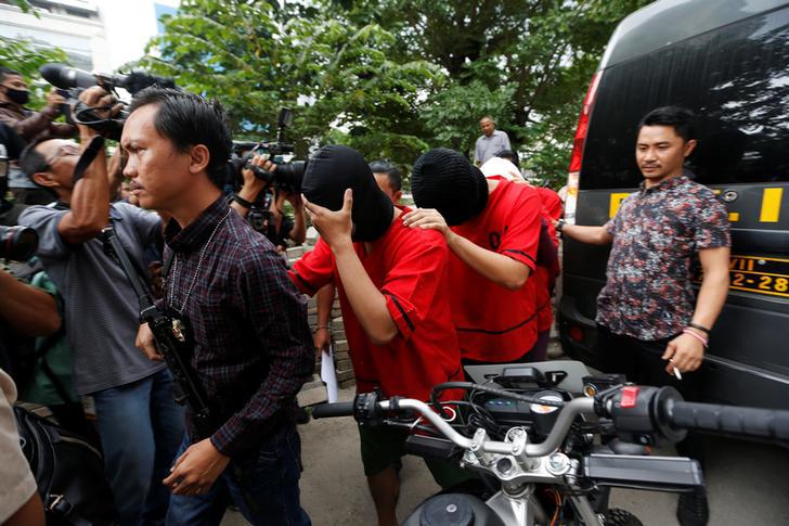 After a weekend raid on a sauna popular among gay men, a plainclothes policeman holds a rifle as he escorts several men during a police investigation in Jakarta, Indonesia