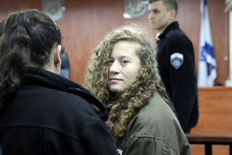 Gadis Palestina Ahed Tamimi (kanan) memasuki ruang pengadilan militer bersama sipir penjara Ofer, dekat kota Ramallah, Tepi Barat, 1 Januari 2018.