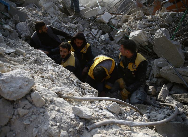 أفراد من الدفاع المدني السوري يبحثون عن ناجين بعد غارة جوية على بلدة حمورية المحاصرة، الغوطة الشرقية، في دمشق، سوريا 9 يناير/كانون الثاني 2018. © 2018 رويترز