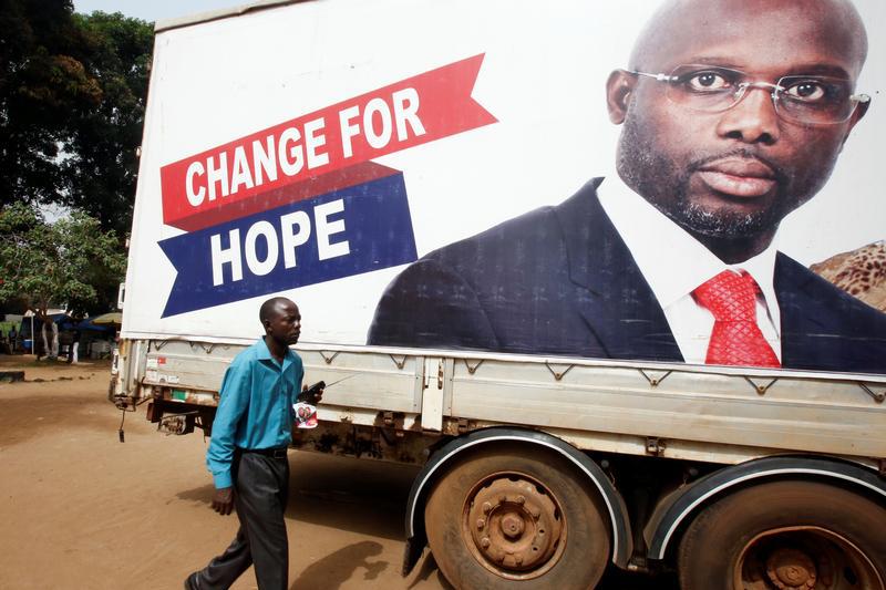 A supporter walks by an image of George Weah, President of Liberia, in Monrovia, Liberia, December 27, 2017. © 2017 Reuters