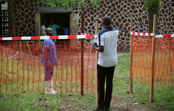 Un habitant parle avec un travailleur médical de l’autre côté d’un cordon près de la zone d’isolement préparée pour recevoir des cas présumés d’Ebola, à l’hôpital général de Mbandaka, en République démocratique du Congo, le 20 mai 2018.