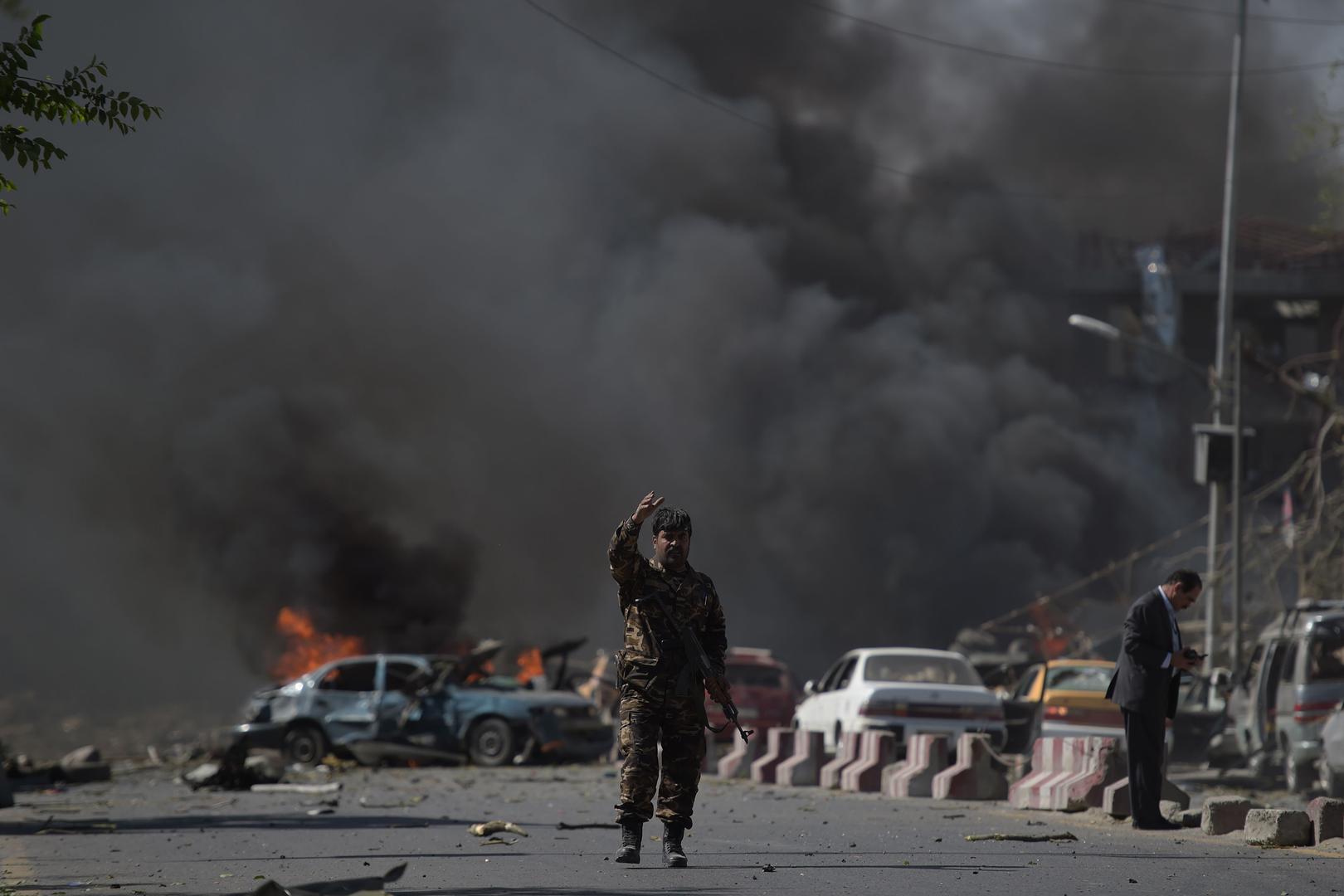 Un membre des forces de sécurité afghanes fait un signe de la main, devant le lieu d'un attentat à la voiture piégée à Kaboul, le 31 mai 2017.