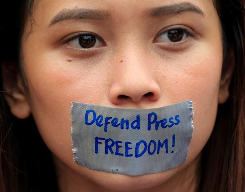 Une jeune femme membre du College Editors Guild (« Association des rédacteurs de journaux universitaires ») aux Philippines, la bouche recouverte d’un ruban adhésif où figure le message « Défendre la liberté de la presse ! », lors d'une manifestation sile