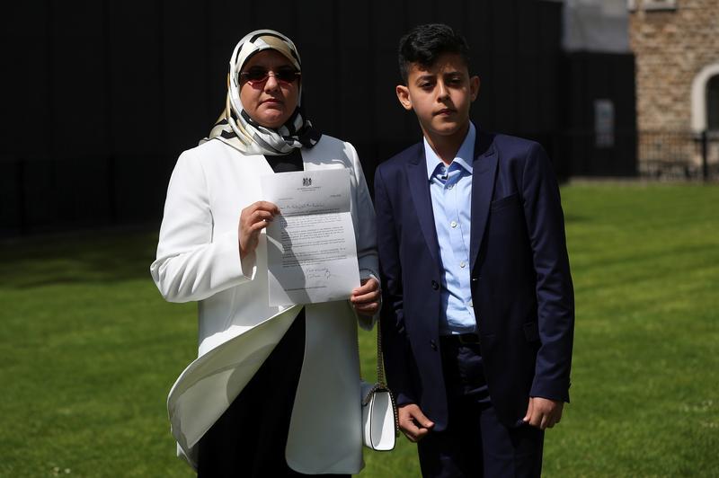 Fatima Boudchar, wife of Libyan politician Hakim Belhadj, stands with their son Abderrahim, as she holds a letter of apology from Prime Minister Theresa May.