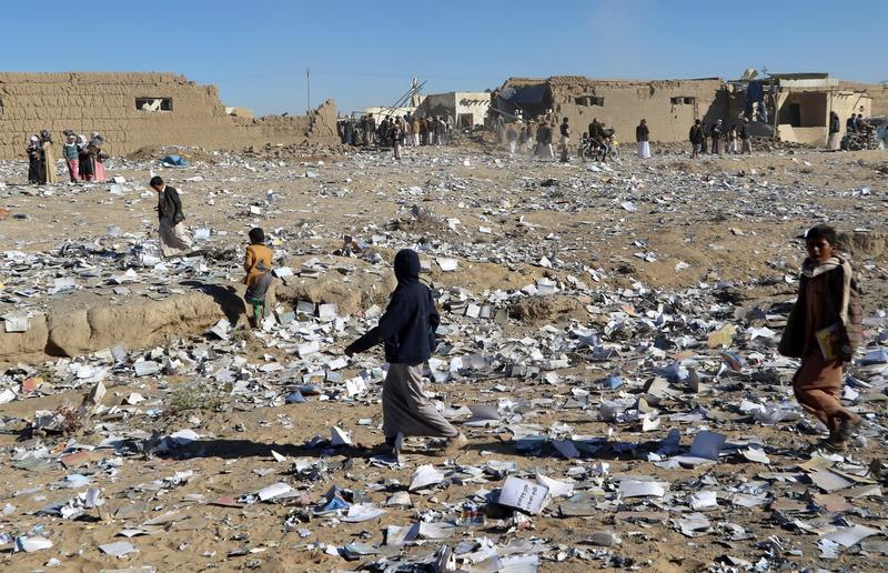 صبيان يمشون على كتب مدرسية مبعثرة على الأرض بعد استهداف غارة جوية لمخزن للكتب المدرسية في مدينة صعدة في شمال غرب اليمن يناير/كانون الثاني 2018.