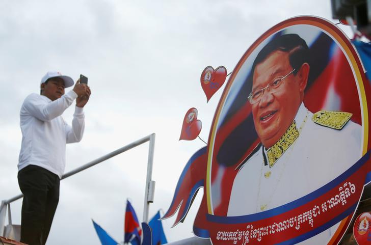 A supporter of the ruling Cambodian People's Party (CPP) uses a mobile phone to photograph a portrait of CPP president Hun Sen during an election campaign in Phnom Penh, Cambodia, July 7, 2018. REUTERS/Samrang Pring