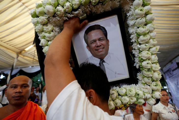 A man holds portrait of Kem Ley, an anti-government figure and the head of a grassroots advocacy group, "Khmer for Khmer", shot dead on July 10, as they attend a funeral procession to carry his body to his hometown, in Phnom Penh July 24, 2016.