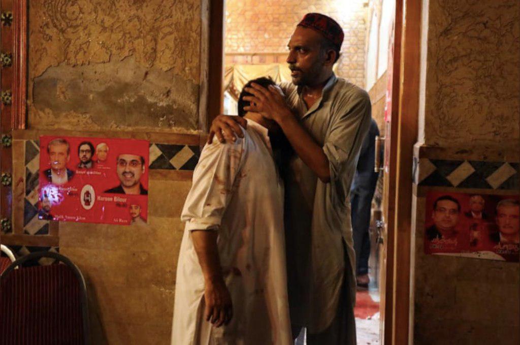 A political party worker comforts another after a suicide attack during an election campaign meeting in Peshawar, Pakistan, July 10, 2018.